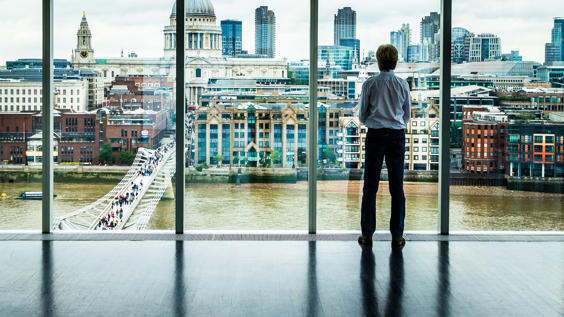 Businessman looking out of window at London skyline
